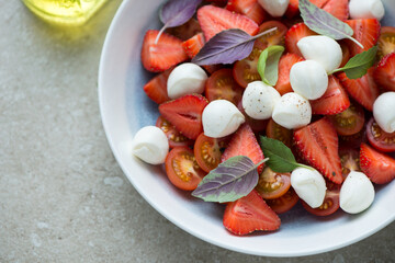 Caprese with fresh strawberry, cherry tomatoes, mini mozzarella and fresh basil, horizontal shot, closeup