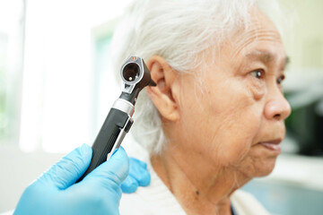 Otolaryngologist or ENT physician doctor examining senior patient ear with otoscope, hearing loss problem.