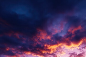 Obraz premium Dramatic Cloudscape at Dusk Fiery Orange and Pink Clouds Meet Dark Blue Sky