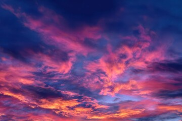 Fototapeta premium Dramatic Pink and Orange Clouds at Dusk Against a Deep Blue Sky Backdrop