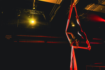 A person is performing a trick on a tightrope. The tightrope is red and the person is wearing black