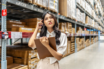 Focused on her task, Young asian woman holding clipboard meticulously updates inventory records, thinking about project while surrounded by shelves filled with various products in a warehouse