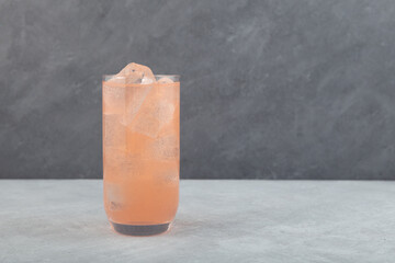 Grapefruit cocktail with ice cubes in tall drinking glass. Refreshing summer fruits drink with soda...