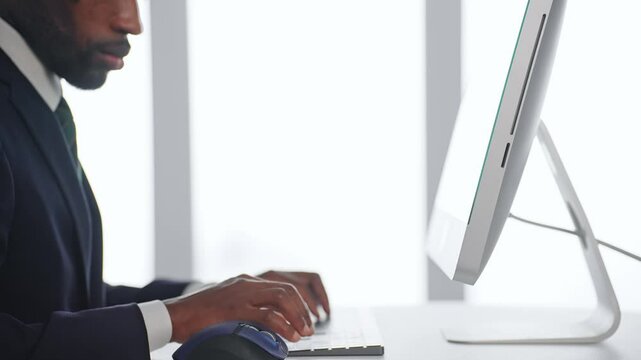 A black male business person working on a desktop PC in an office