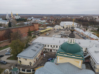 City Kolomna with a large green dome on top of a building. There are many cars and buses parked in the area
