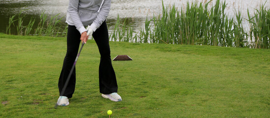 Female Golfer Preparing to Swing at a Tournament Near a Pond
