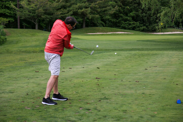 Man Swinging Golf Club on a Lush Green Course During Daylight
