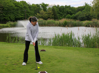 Woman Practicing Golf Swing on a Course by a Lake