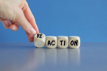 Hand turns dice and changes the word action to reaction. Beautiful blue background. Business and...