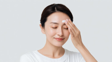 Spreading cream across forehead using upward strokes asian