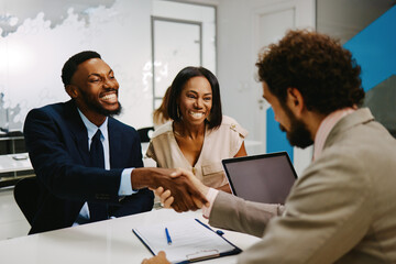 Couple meeting with financial advisor shaking hands after successful discussing investments and financial planning