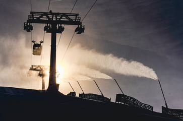 A ski lift is in the background of a snowy mountain. The ski lift is in the foreground of the image