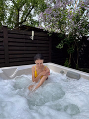 Young brunette woman relaxing in jacuzzi spa bath in spring outdoor