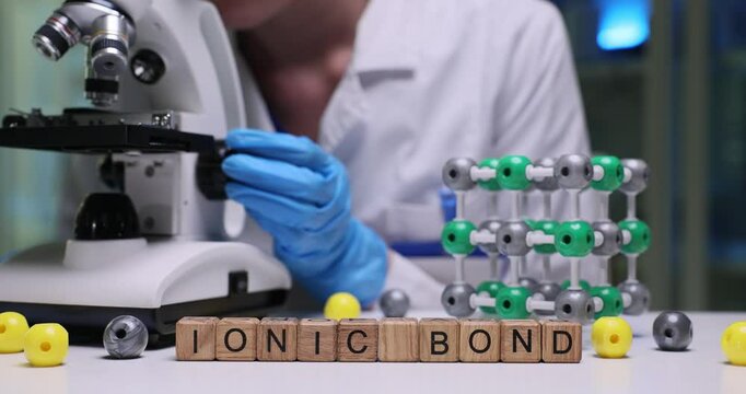A dedicated scientist carefully examines ionic bonds using a microscope, showcasing detailed molecular models