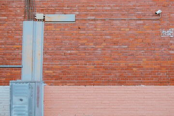 Brick wall with communications on it and video surveillance camera in right corner