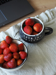 Strawberries in mugs on the tablecloth on the table. Aesthetic dessert