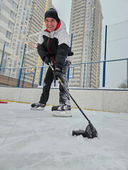 Man is playing ice hockey with a hockey stick. He is wearing a white jacket and black pants near...
