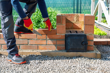 man building bricks barbeque at the backyard.