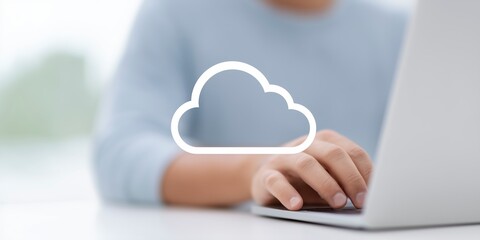 Person using laptop with cloud icon overlay, engaged in digital work, showcasing modern technology and connectivity in a bright workspace with soft natural light
