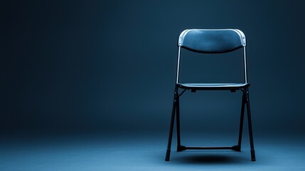 A blue folding chair against a dark blue background. The chair is empty and has a minimalist design.