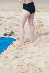 Lower part view of an unidentified person on the sand of a beach during strong sunlight. Activity, direction, path.