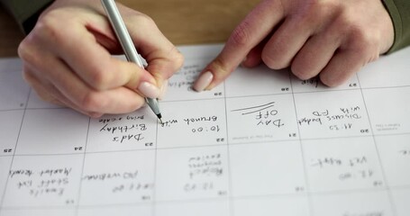 Woman writes appointment in business calendar pointing at box for date. Organizing professional schedule with precise planning during work shifts