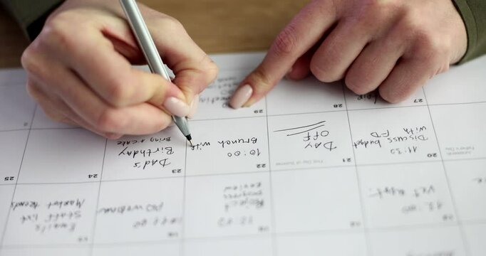 Woman writes appointment in business calendar pointing at box for date. Organizing professional schedule with precise planning during work shifts