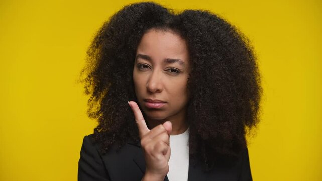 Serious woman making warning gesture on yellow