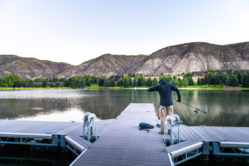 Nottingham lake park dock in Avon, Colorado with man preparing on fishing pier at sunrise in small mountain village ski town city cold summer