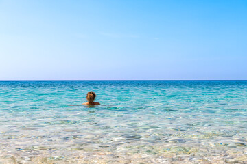 Seychelles beach, Ikaria island Greece in Magganitis with young woman swimming bathing in Icarian sea with crystal clear turquoise water