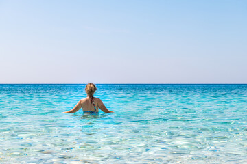 Seychelles beach, Ikaria island Greece in Magganitis with young woman swimming in Icarian sea with crystal clear turquoise water