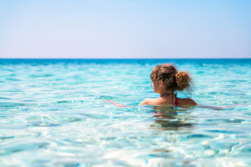 Seychelles beach, Ikaria island Greece in Magganitis with one young woman swimming bathing in Icarian sea with crystal clear turquoise water