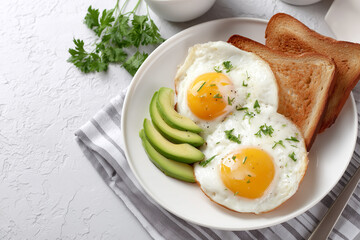 Breakfast plate with eggs, toast, and avocado slices in morning light