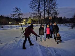 Group of people are standing in the snow, some of them are holding sticks. One of the people is...