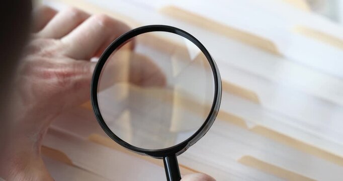 Investigator examines files with magnifying glass conducting thorough search for crucial details. View emphasizes meticulous investigation nature