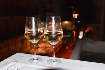 Two glasses of wine on the balcony ledge of a hotel in the summer evening, at night. Vacation time.