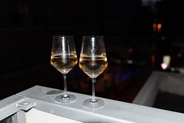 Two glasses of wine on the balcony ledge of a hotel in the summer evening, at night. Vacation time.