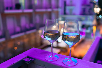 Two glasses of wine on the balcony ledge of a hotel in the summer evening, at night. Vacation time.