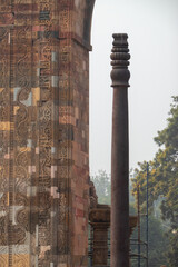 The iron pillar of Delhi, overview with stone carving in foreground