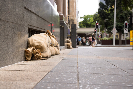 Sandbags along the footpath lining the lower windows of a building in Brisbane CBD before a cyclone