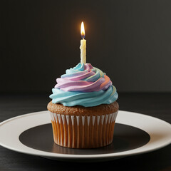 Cupcake with pastel blue and purple frosting topped with lit birthday candle on white plate, creating warm and festive atmosphere