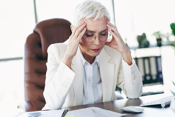 Elegant mature businesswoman working in her office, focusing on tasks, emphasizing professionalism,...