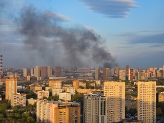 City with a lot of buildings and smoke in the air. The smoke is coming from a fire