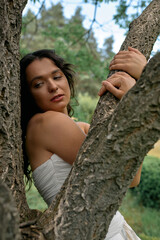 Young woman enjoying a summer day outdoors in a white dress beside a majestic tree