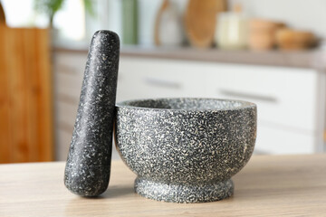 Stone mortar and pestle on wooden table in kitchen