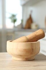 Mortar and pestle on wooden table in kitchen, closeup