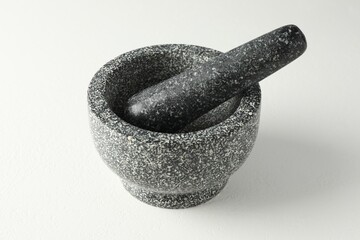 Stone mortar and pestle on white table, closeup