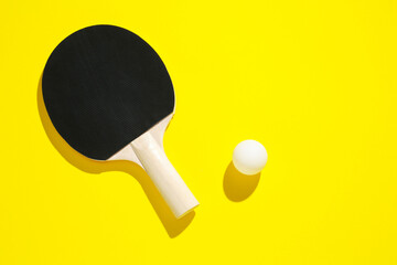 Ping pong racket and ball on yellow background, top view. Space for text