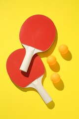 Ping pong rackets and balls on yellow background, flat lay