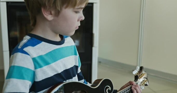 Caucasian Kid Play Mandolin at Home. European Boy Practice Music 4K 10-bit